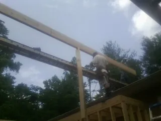 Carpenter setting a ridge beam over a new addition frame — Ice Dam Removal by Roofing Brothers in Still Pond
