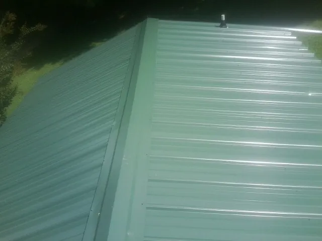 New green metal panels meeting at the ridge of a roof — Flat Roof Repair work by our crew in Still Pond