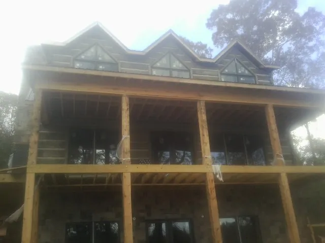 Dormers and porch framing on a large log home under construction — Roof Coating work by our crew in Still Pond