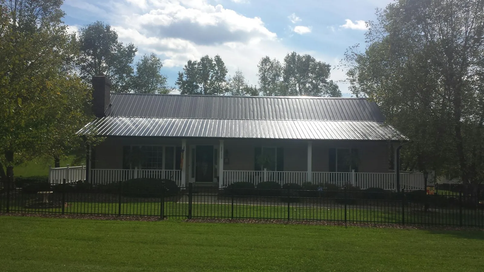 Gray metal roof on a brick ranch with a full width front porch — Gutter Guard Installation work by our crew in Still Pond
