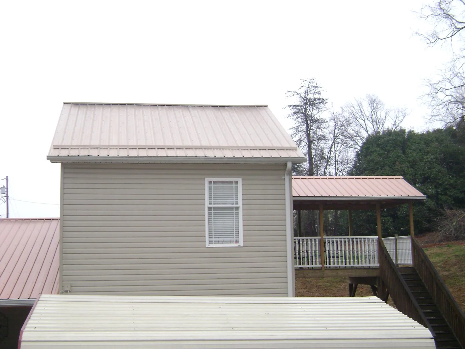 Tan metal roofs on a two story addition and attached porch, from a Roof Replacement job in Still Pond