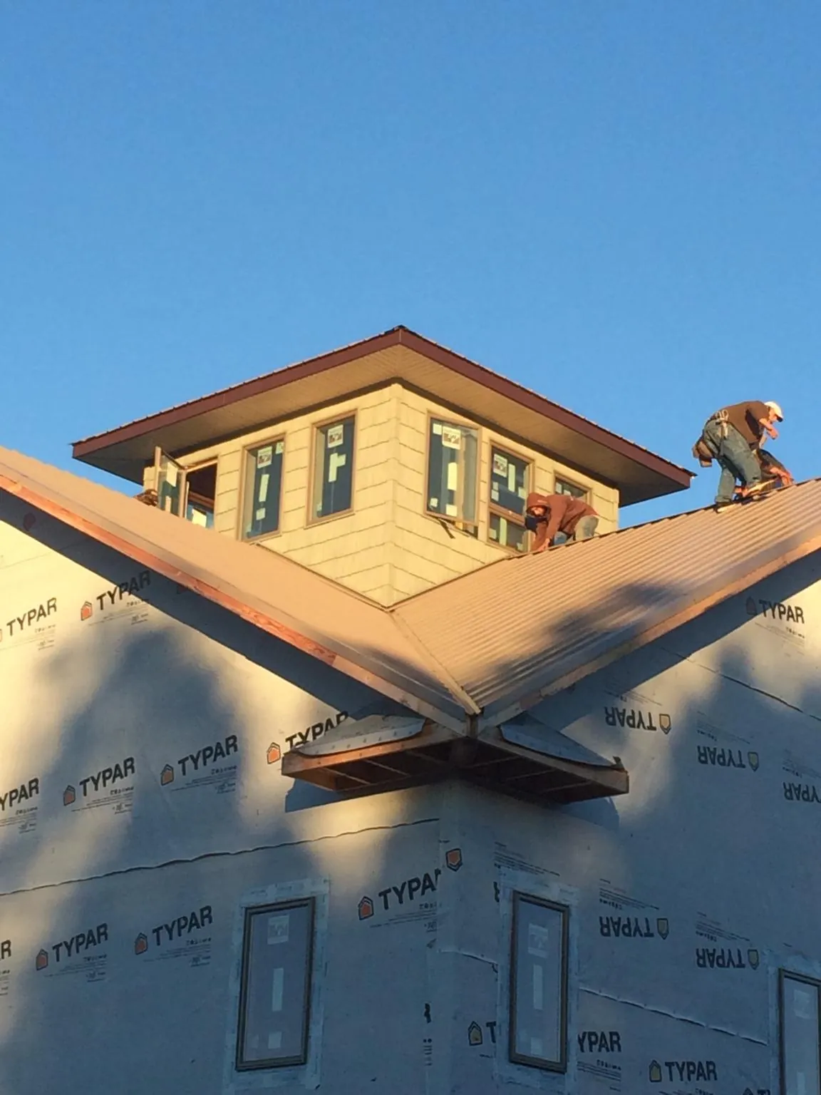 Roofers working around a rooftop cupola on a new metal roof at sunset — Roof Waterproofing in Still Pond by Roofing Brothers